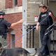 A boston police officer wearing a Boston Police Bomb Squad outfit holds a door for another officer with holding a leash for a dog.